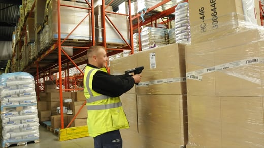 Mies skannaa laatikon viivakoodin varastossa